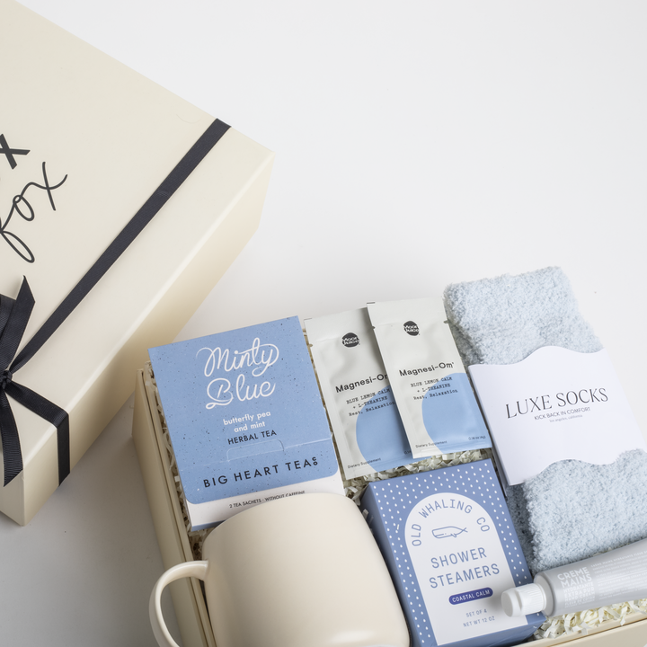 Gift set with tea packages, shower steamers, and socks on a white surface