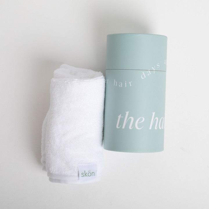 Skincare product and towel on a light gray background