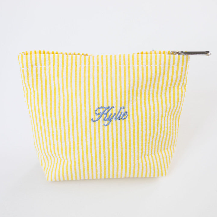 Yellow striped pouch with 'Kylie' embroidery on a white background