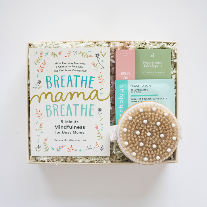 Product set with 'Breathe Mama Breathe' book, oil, and bath brush in a box on a white background