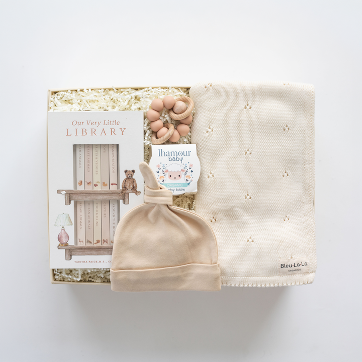 Baby hat, blanket, and book set on a white background