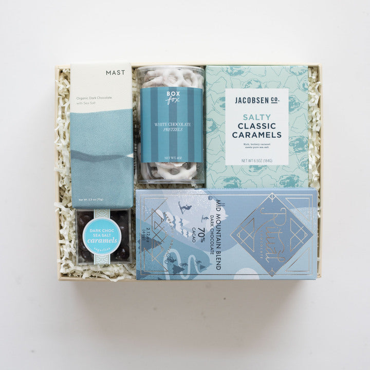 Gift box with various products including chocolates and caramels on a white background