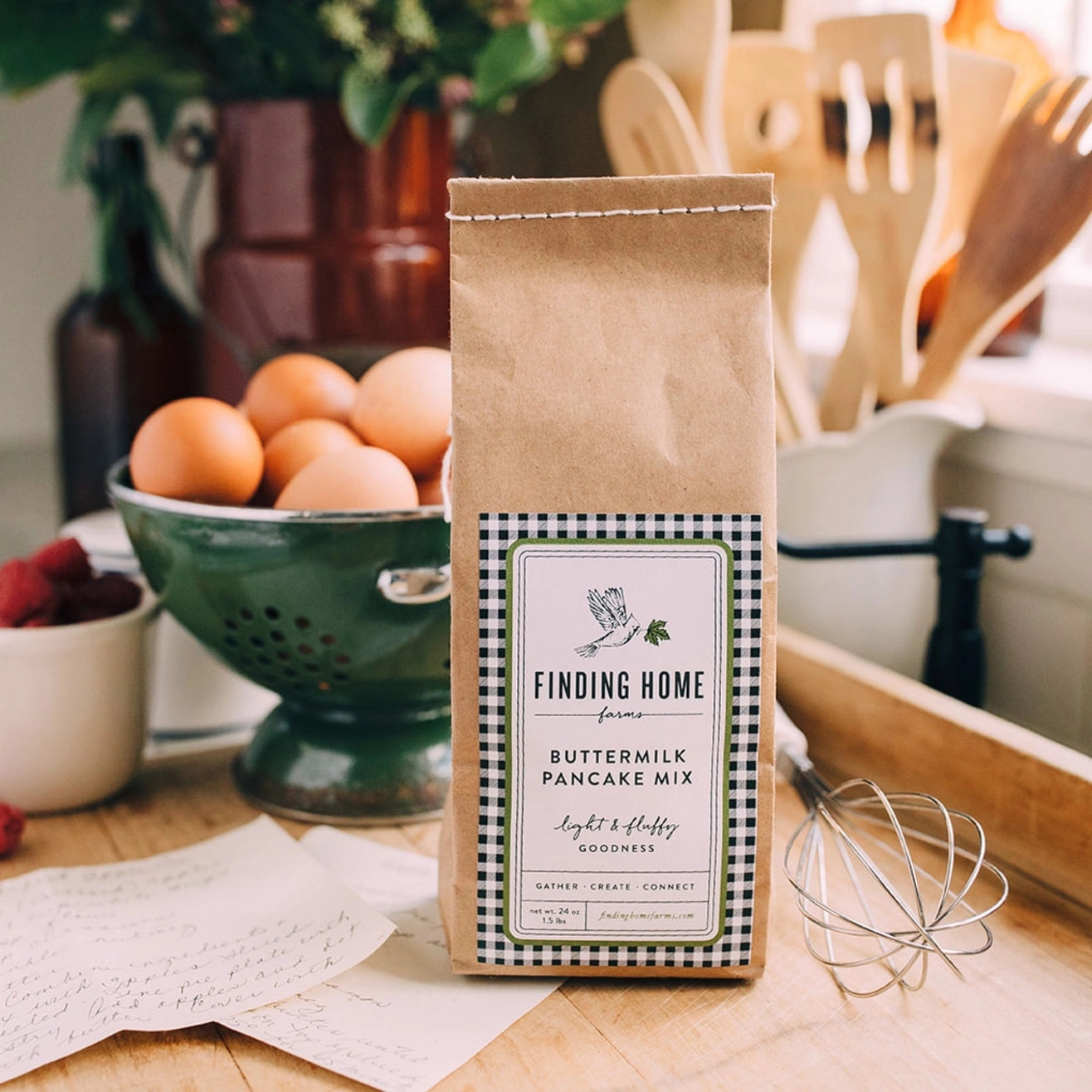 Bag of Finding Home Farms Buttermilk Pancake Mix on a kitchen counter with eggs and utensils.