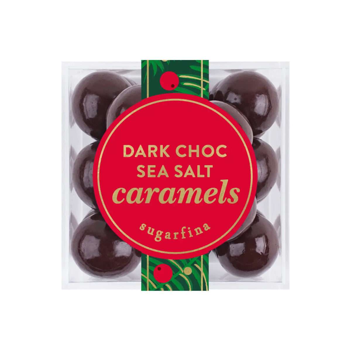 A clear square plastic box of Sugarfina Dark Choc Sea Salt Caramels, featuring eight glossy dark chocolate candies and a prominent red circular label with gold lettering and a green decorative ribbon.