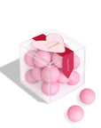 Pink candies in a clear cube with a red and white label on a white background