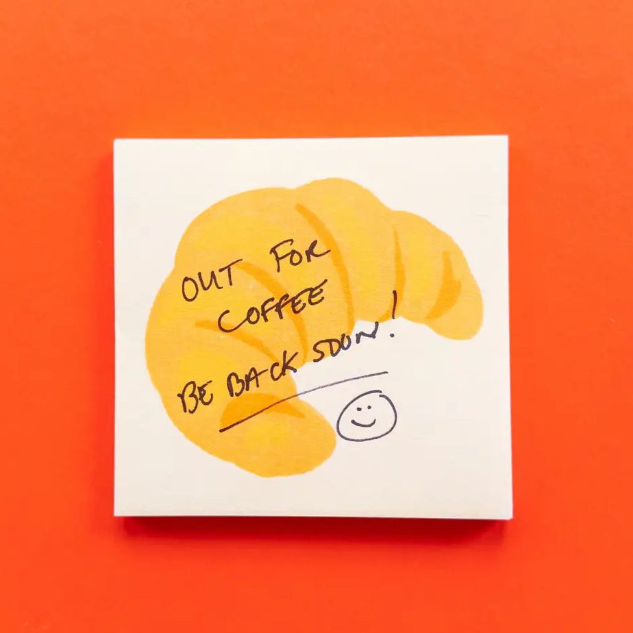 Note with a cartoon face and text 'Out for coffee, be back soon!' on an orange background