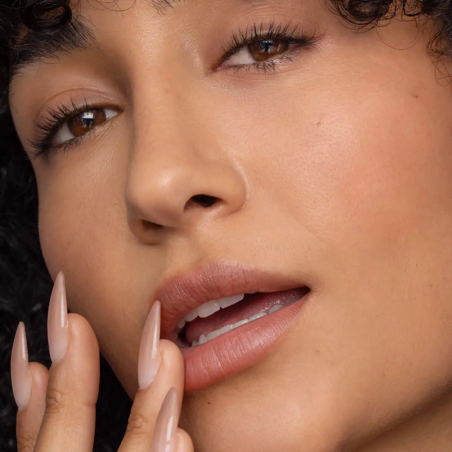 Close-up of a woman's face with a focus on her lips and nails.