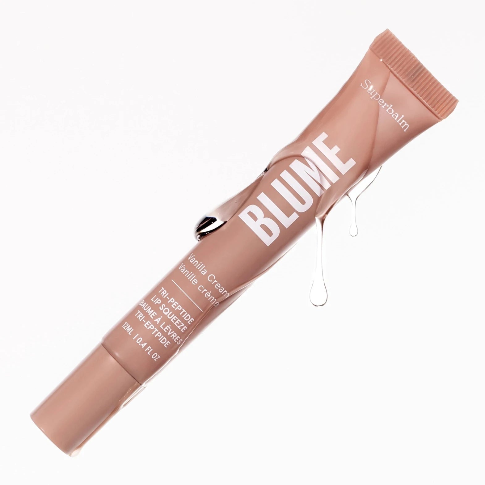 The image shows a tube of "Blume Superbalm" in a soft, beige-pink color. The product label mentions the scent or flavor as "Vanilla Cream" and highlights that it contains a "Tri-Peptide" formula, suggesting nourishing or restorative properties. The tube has a glossy finish, with some transparent liquid droplets running down the side, giving it a fresh, hydrating appearance. The volume is indicated as 12 mL (0.41 fl oz). The clean, minimal background emphasizes the elegance and sleek design of the balm.
