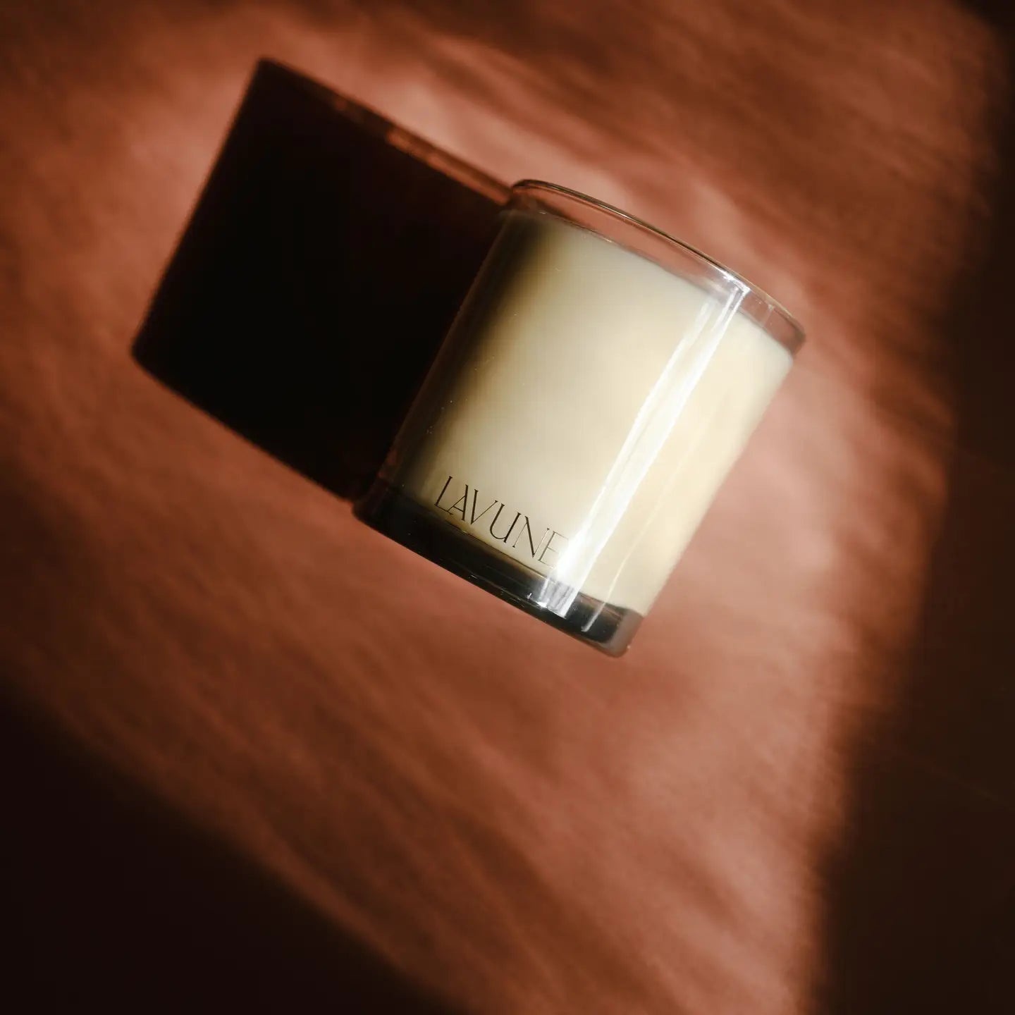 Candle with 'LAVUNE' branding on a wooden surface