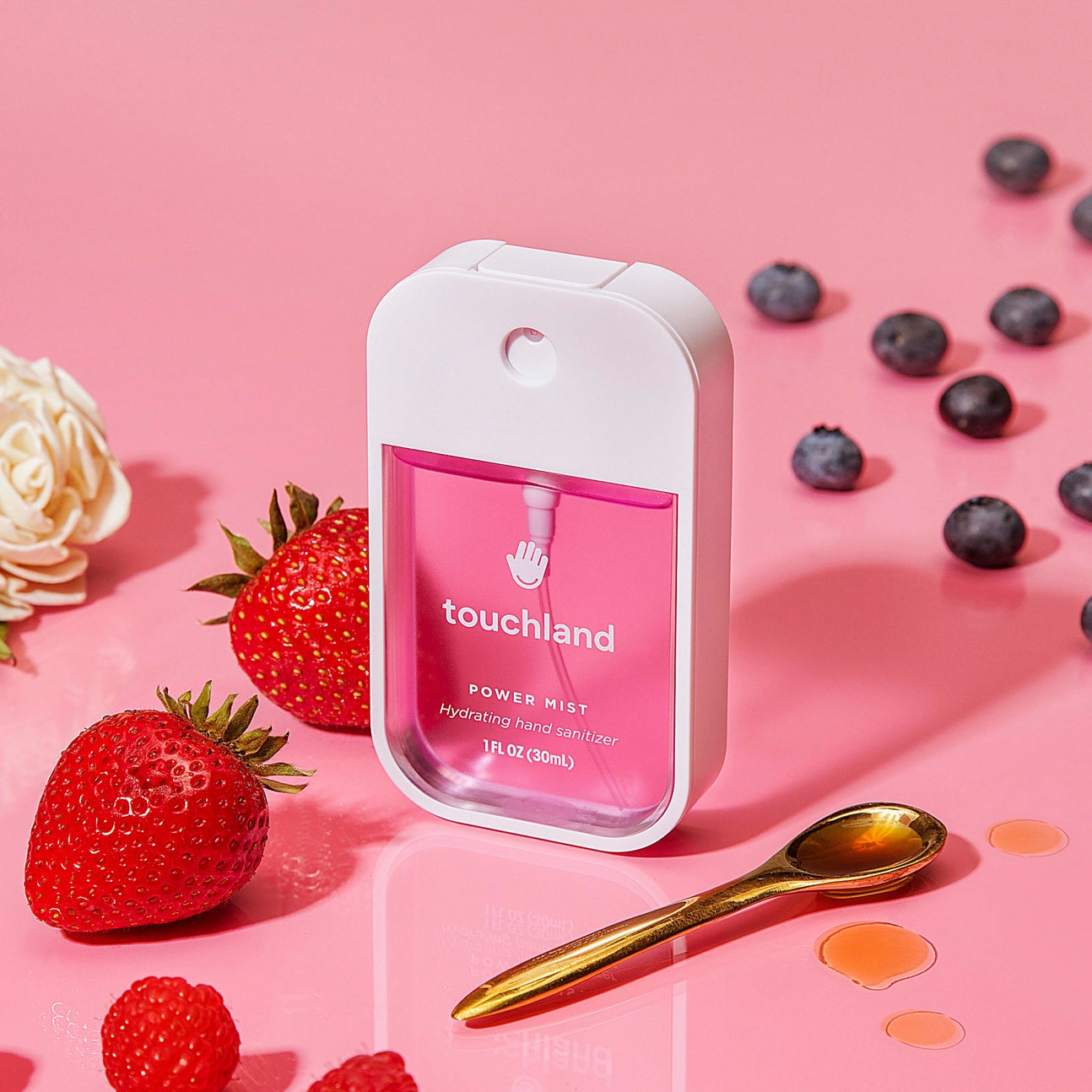 pink hand sanitizer surrounded by berries