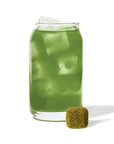 Green drink with ice cubes in a glass on a white background