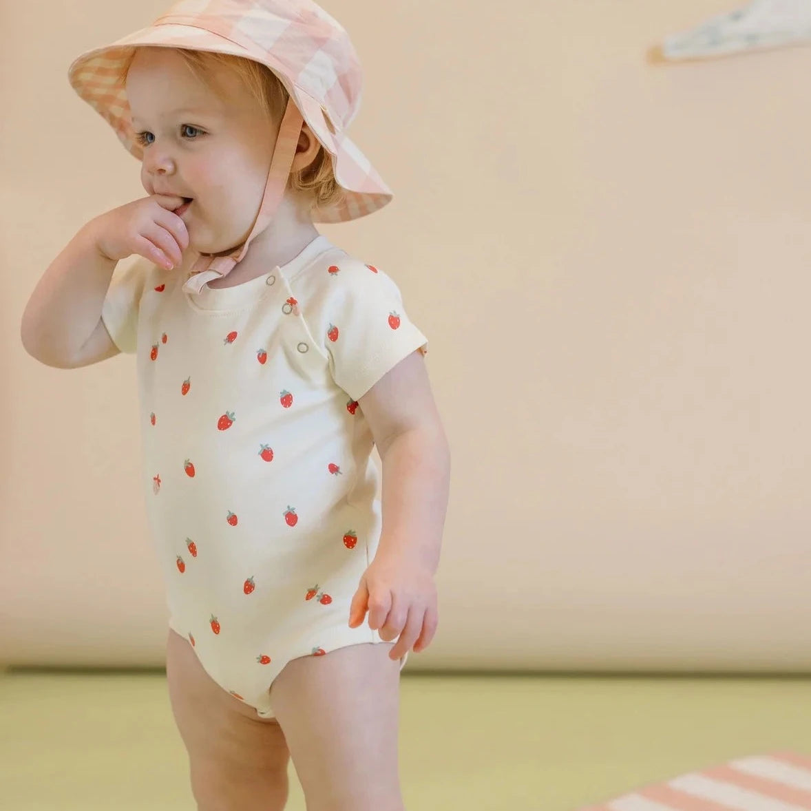 baby wearing strawberry front snap one piece 