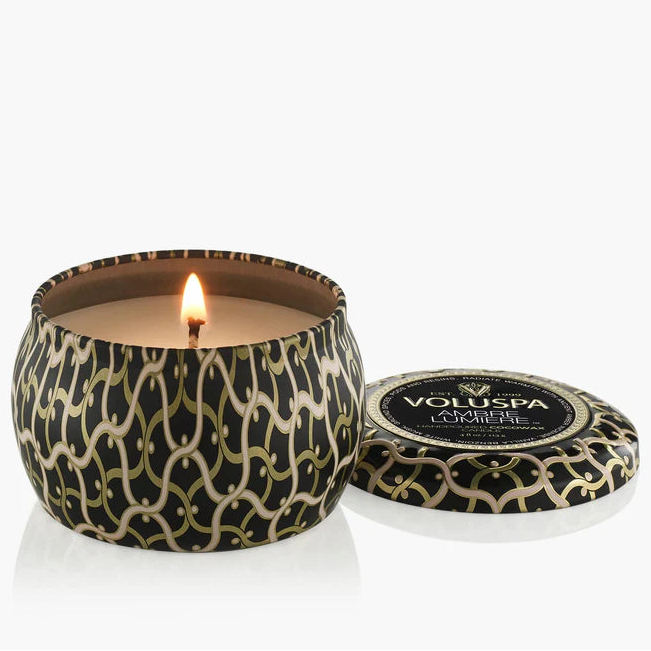 Candle in a decorative container with 'Voluspa' branding on a white background