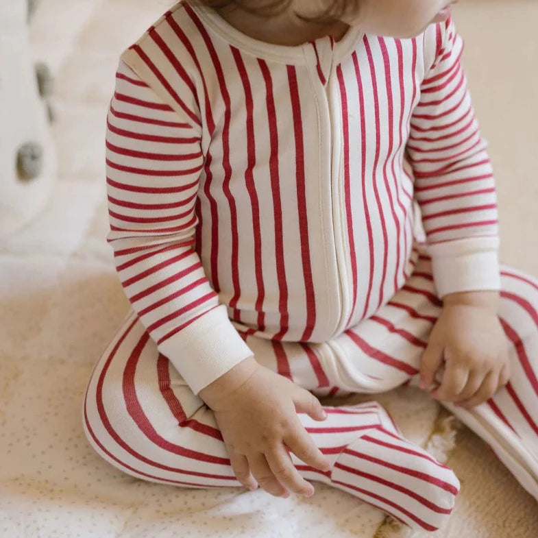baby sitting and wearing red stripped baby sleeper footies pajama