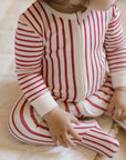 baby sitting and wearing red stripped baby sleeper footies pajama