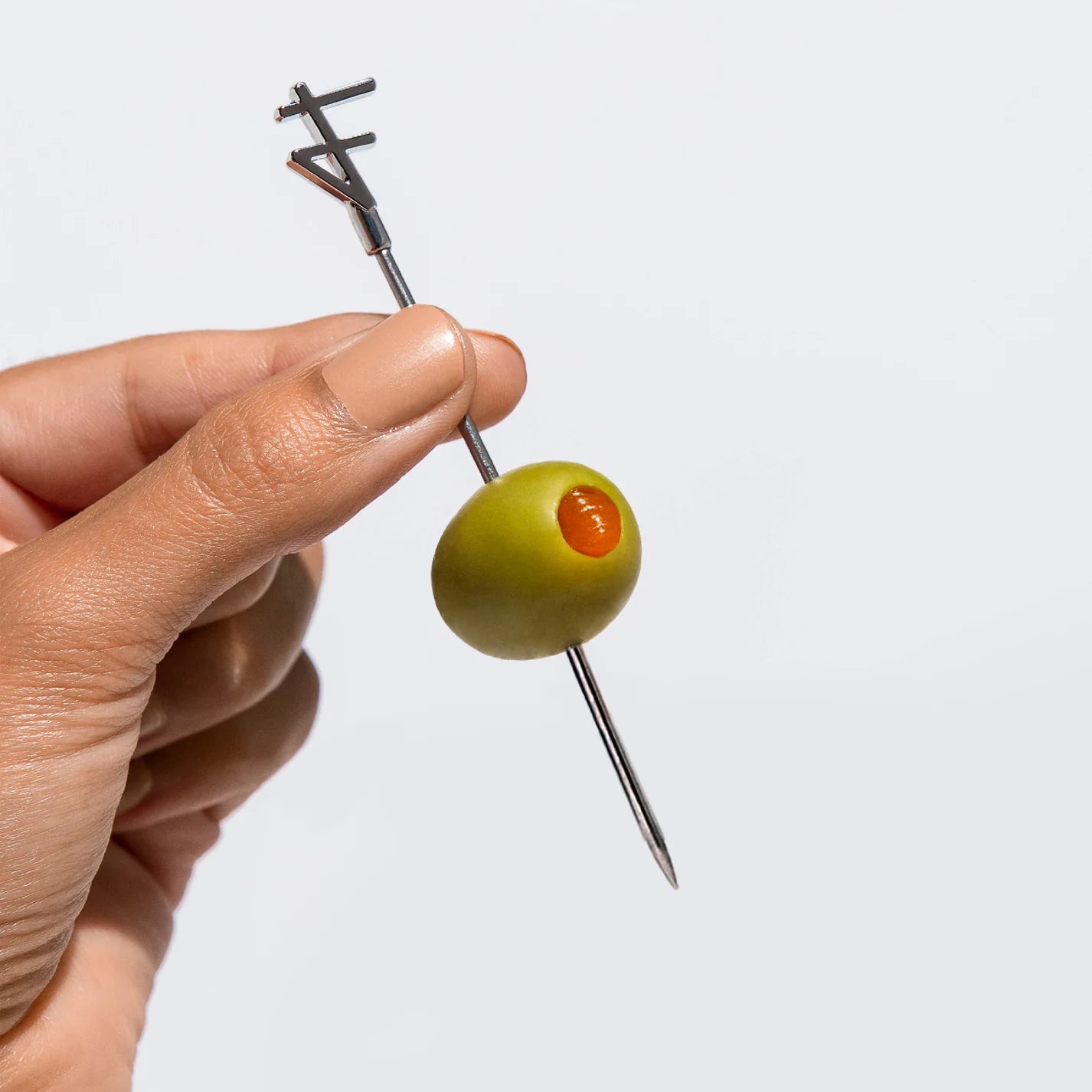 Pimento Pepper Stuffed Olive on cocktail pick held by woman