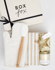 The BAKING box in creme, which includes an oven mitt, spatula, striped dish towel, cookie cutters and a sugar cookie candle.