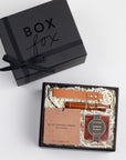 BLACK BOXFOX box displayed open with a Brown Leather Keychain, Tobacco Car Fragrance, Bourbon Toothpicks, and Bourbon Bears.