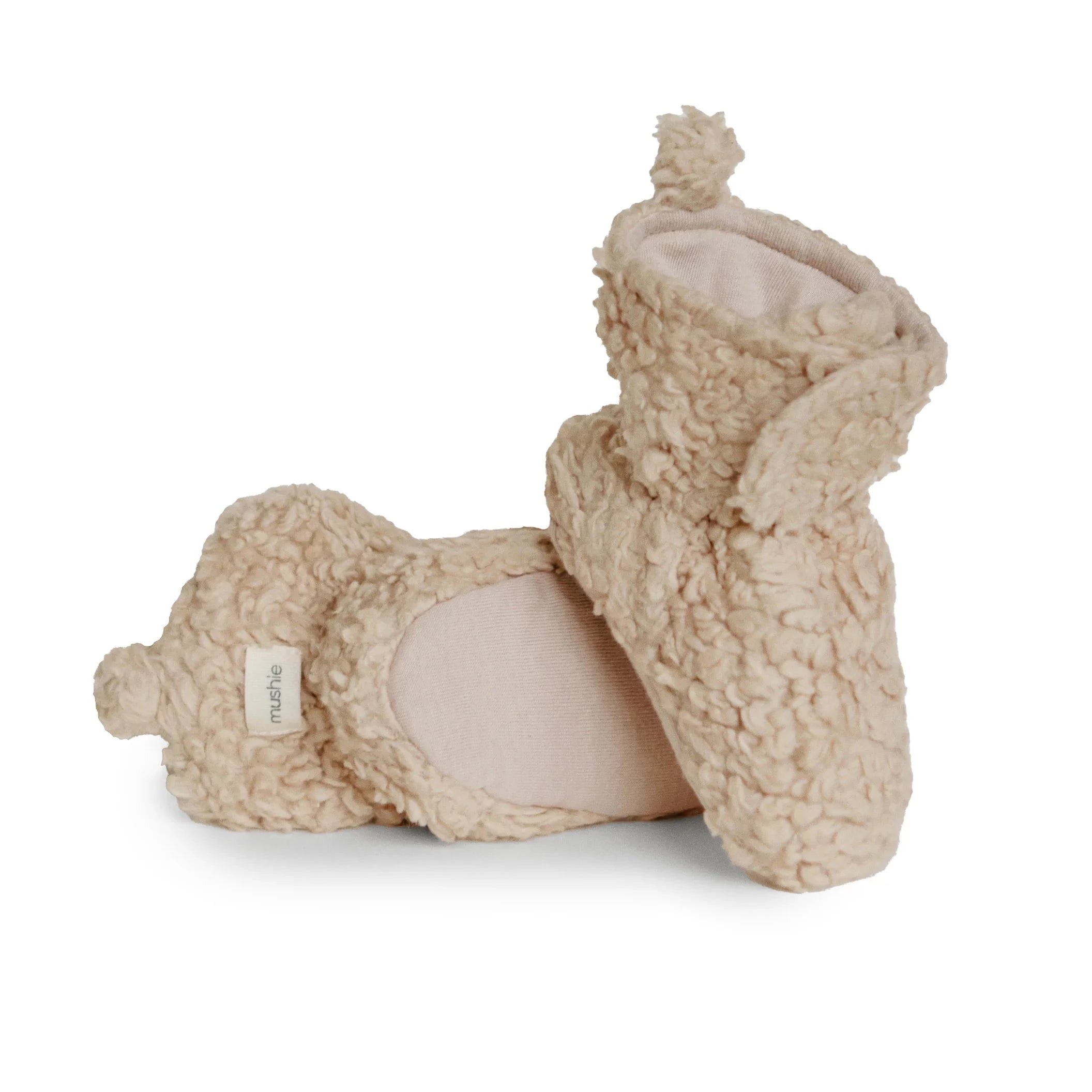 light brow fuzzy booties. back of booties have beige mushie tag. booties have velcro strap in the front
