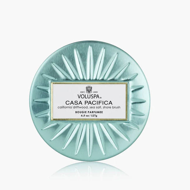 Round teal Voluspa candle with label on a white background