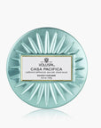 Round teal Voluspa candle with label on a white background