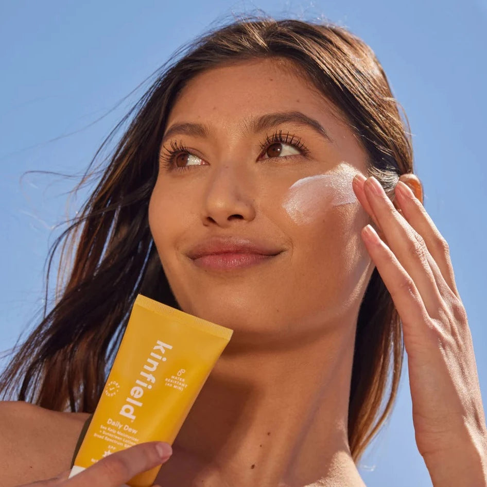 Girl applying Sunglow SPF 35 on cheek while holding tube
