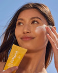 Girl applying Sunglow SPF 35 on cheek while holding tube