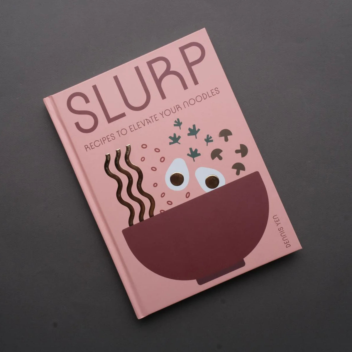 Book titled 'SLURP' with a pink cover and bowl illustration on a dark background