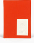 bright red notebook cover with white square on bottom right hand side. Square has black text describing notebook features
