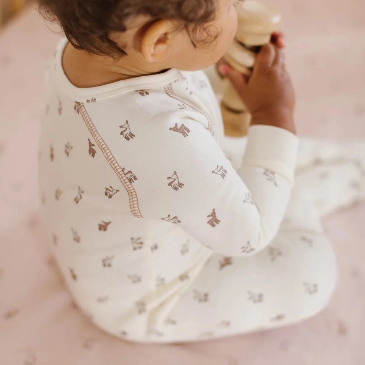 baby wearing fawn printed cream colored footsie pajamas