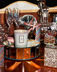 Decorative table setting with a candle, glasses, and decorative items on a reflective surface.