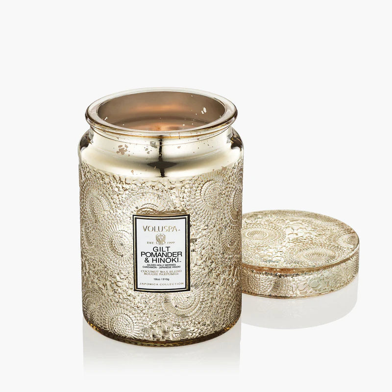Decorative candle in a gold jar with intricate patterns on a white background