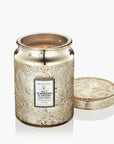 Decorative candle in a gold jar with intricate patterns on a white background