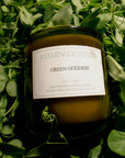 Candle labeled 'Green Goddess' from Flamingo Estate on a bed of green leaves.