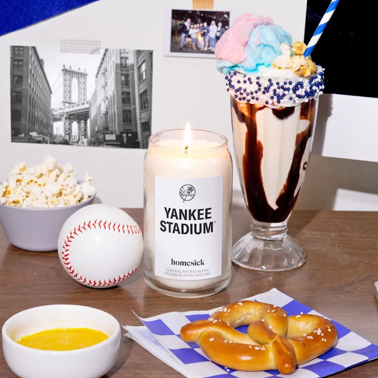 Yankee Stadium Candle surrounded by milkshake, pretzel, baseball, popcorn and photos of NYC