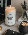 Oracle Park Candle on desk next to computer, matches, pens and notebook