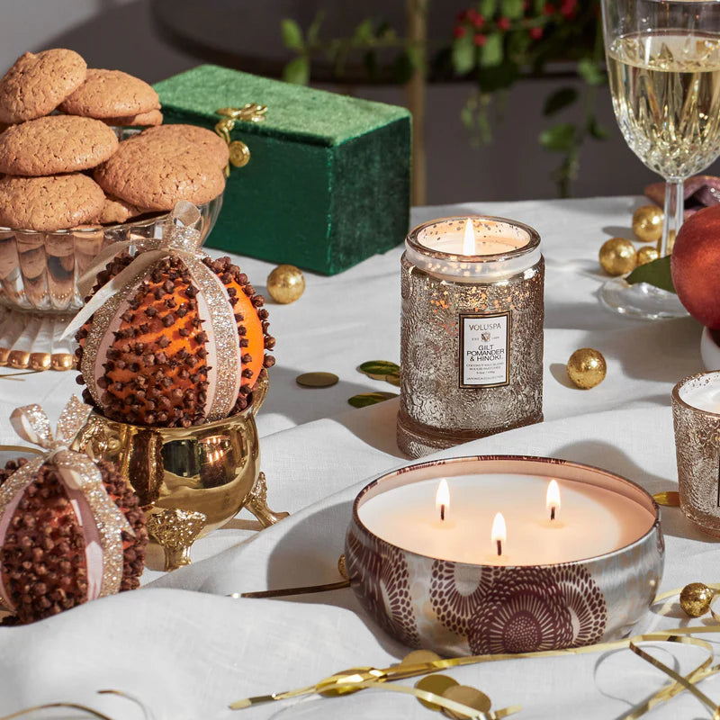 Decorative table setting with candles, cookies, and a wine glass on a white surface.
