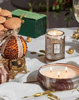 Decorative table setting with candles, cookies, and a wine glass on a white surface.