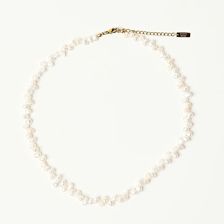 A delicate necklace made of small white beads with a gold-tone clasp, displayed on a clean white background.