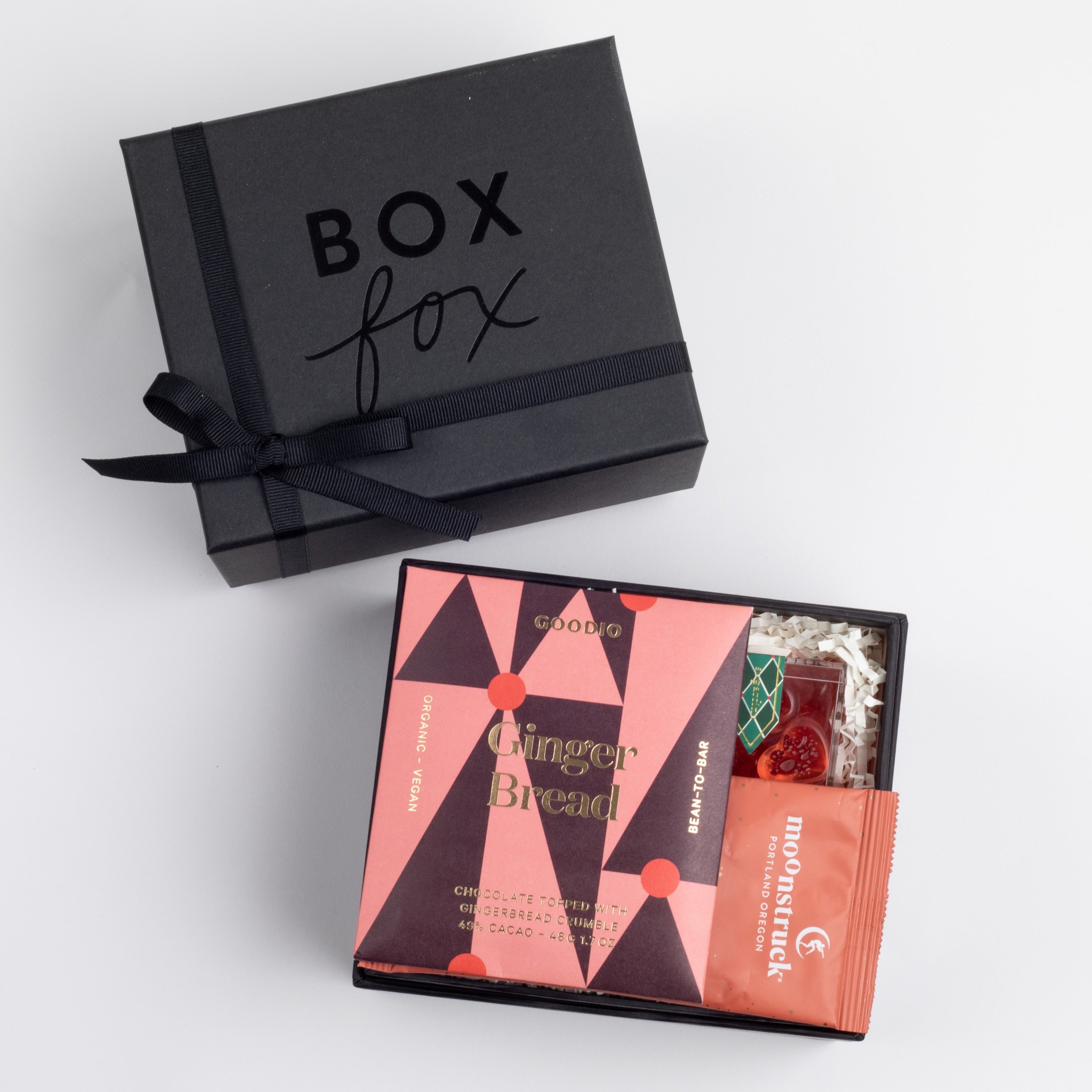 BLACK BOXFOX BOX DISPLAYED OPEN WITH ITEMS: Holiday Hearts, Gingerbread Chocolate Bar, Cinnamon Milk Chocolate Hot Cocoa Packet