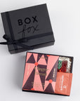 BLACK BOXFOX BOX DISPLAYED OPEN WITH ITEMS: Holiday Hearts, Gingerbread Chocolate Bar, Cinnamon Milk Chocolate Hot Cocoa Packet