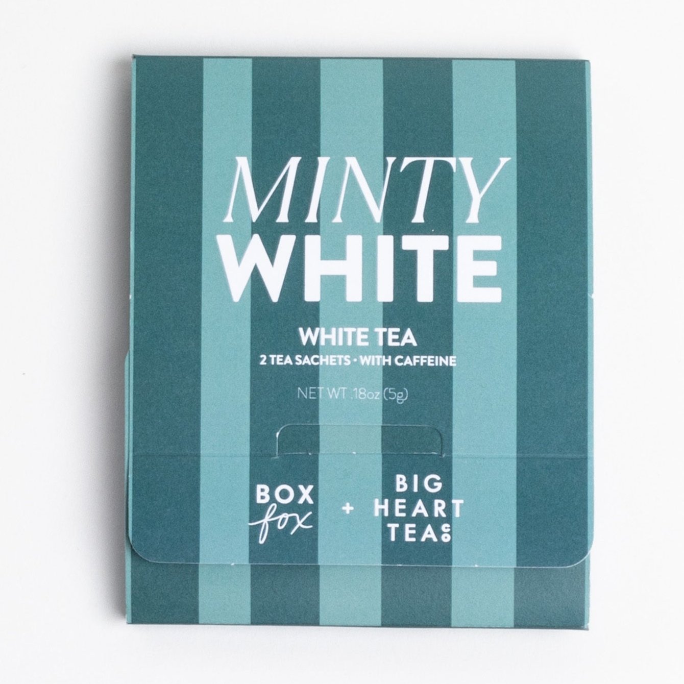 A teal and green-striped box labeled "Minty White" containing two white tea sachets with caffeine. The packaging shows the collaboration between Boxfox and Big Heart Tea Co., with the net weight listed as 0.18 oz (5g).