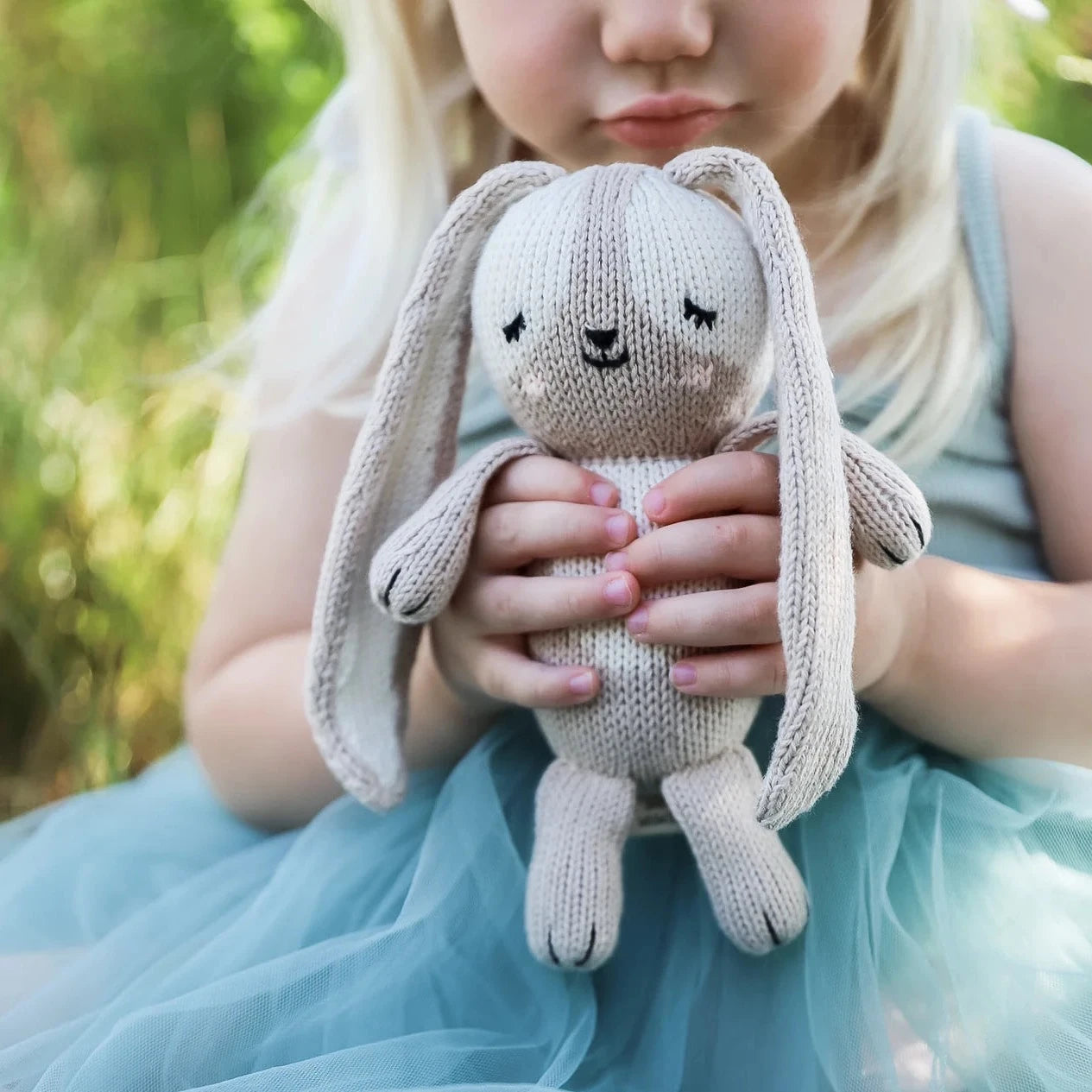 girl holding gray bunny in hands