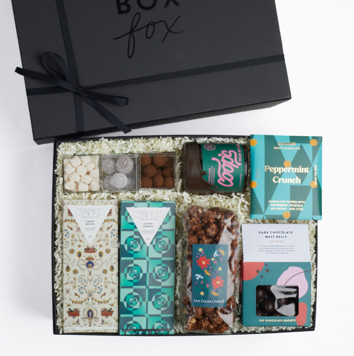 BOXFOX black gift box packed with hot cocoa crunch popcorn, dark chocolate malt balls, compartes chocolate bars, 3 sugarfina candies, vegan hot fudge jar and goodio peppermint crunch chocolate