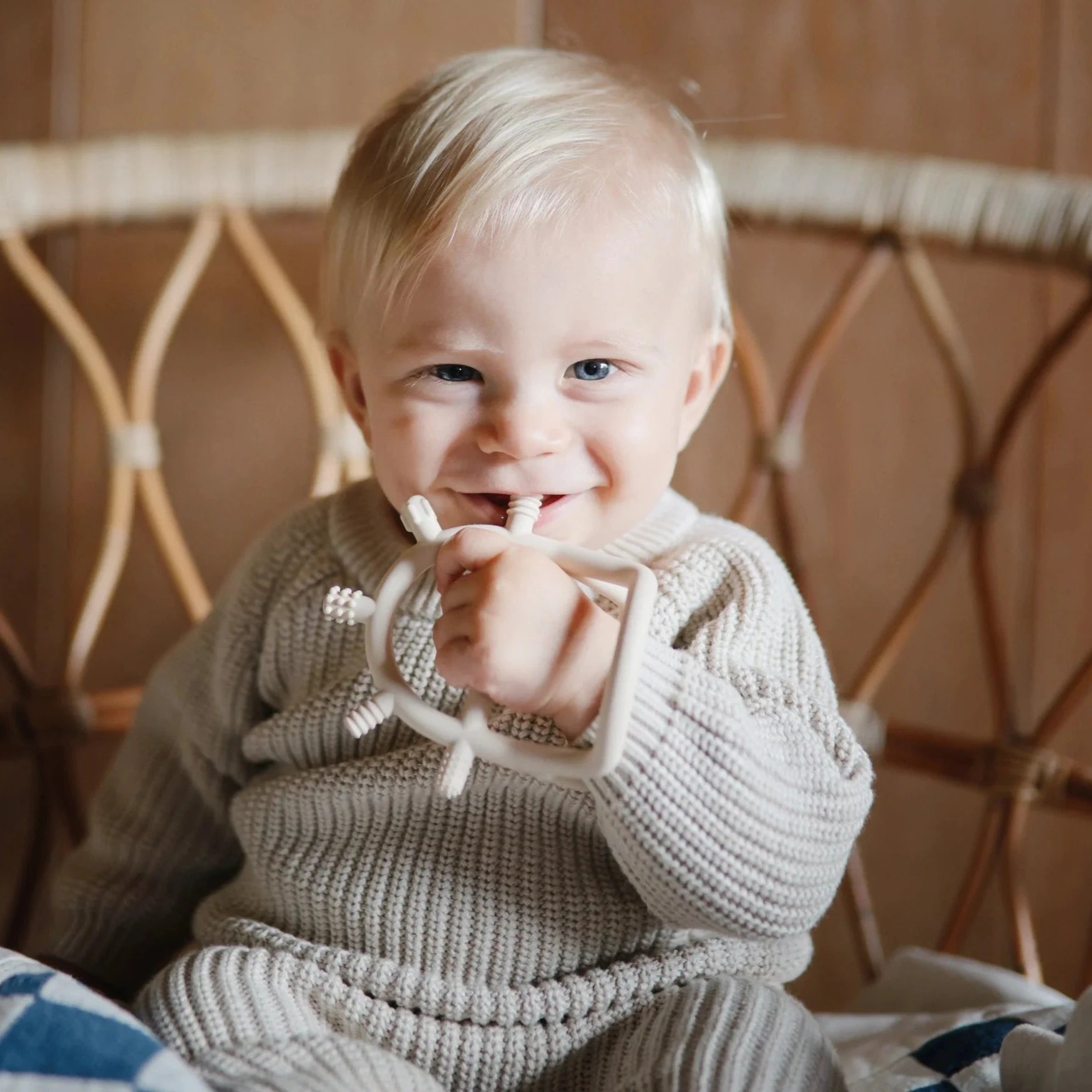 baby holding tan teething toy