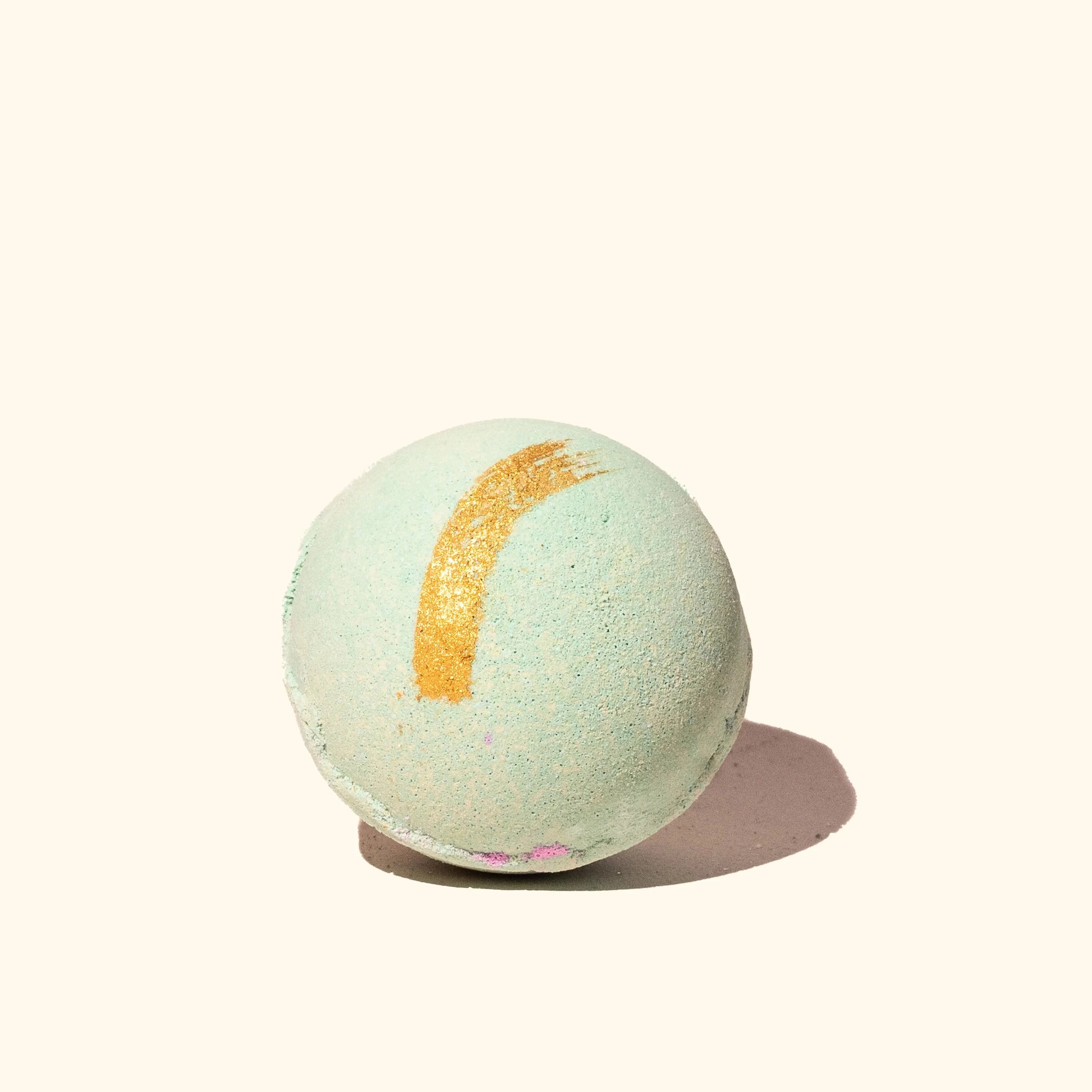 green bath bomb with gold stripe through the top