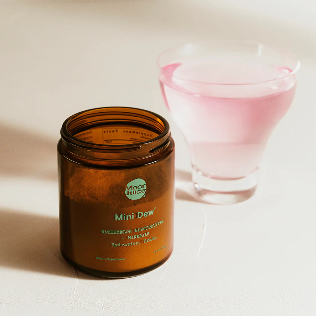 Vice Juice Mini Dew candle in an amber jar with a pink glass in the background.