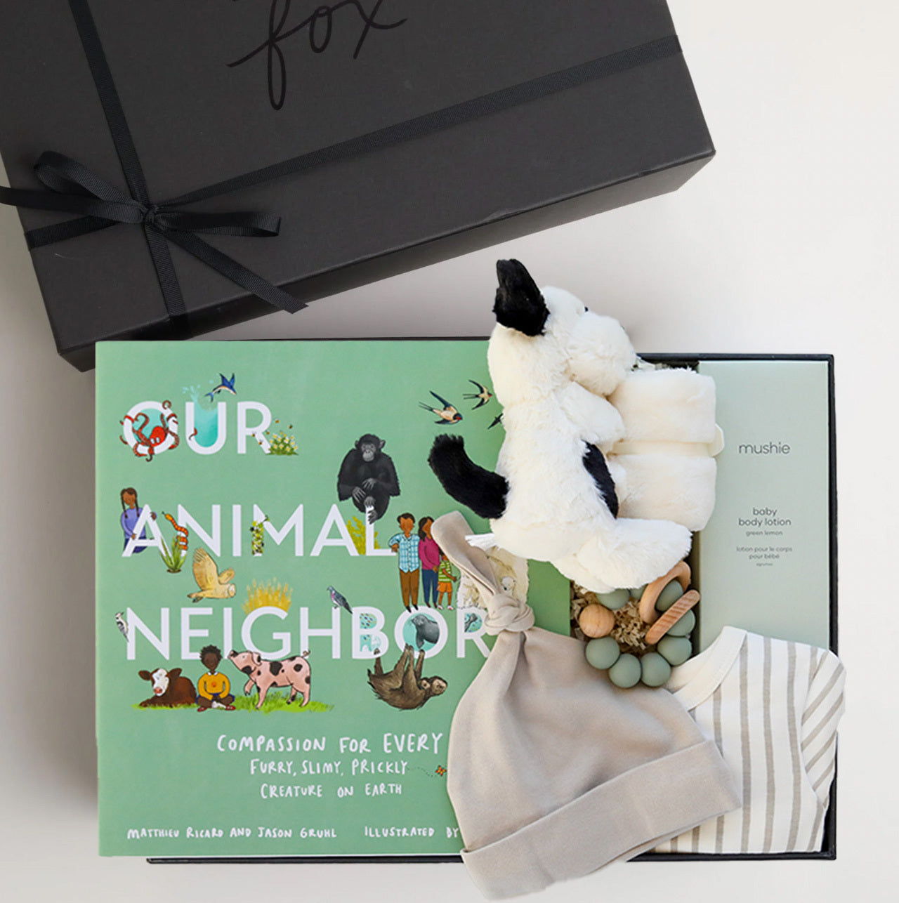 BOXFOX black New Family Gift Box packed with PEHR cozy grey kimono onesie 3-6 months, Jellycat puppy lovey, Our Animal Neighbors book, Pipette baby oil, Alva sage green teether, and Alva grey beanie