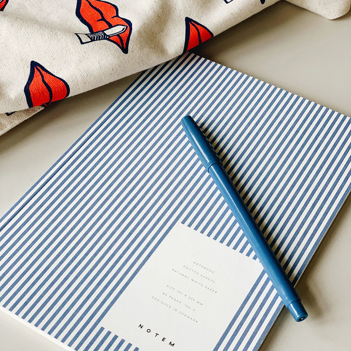 VITA MEDIUM SOFTCOVER NOTEBOOK | BLUE LINES with blue pen next to canvas bag