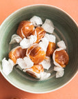 Green ceramic bowl full of caramels wrapped in wax paper